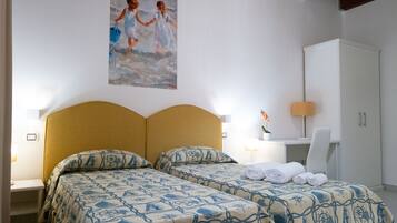 A hotel room with two beds, a desk, a chair, and a painting on the wall.