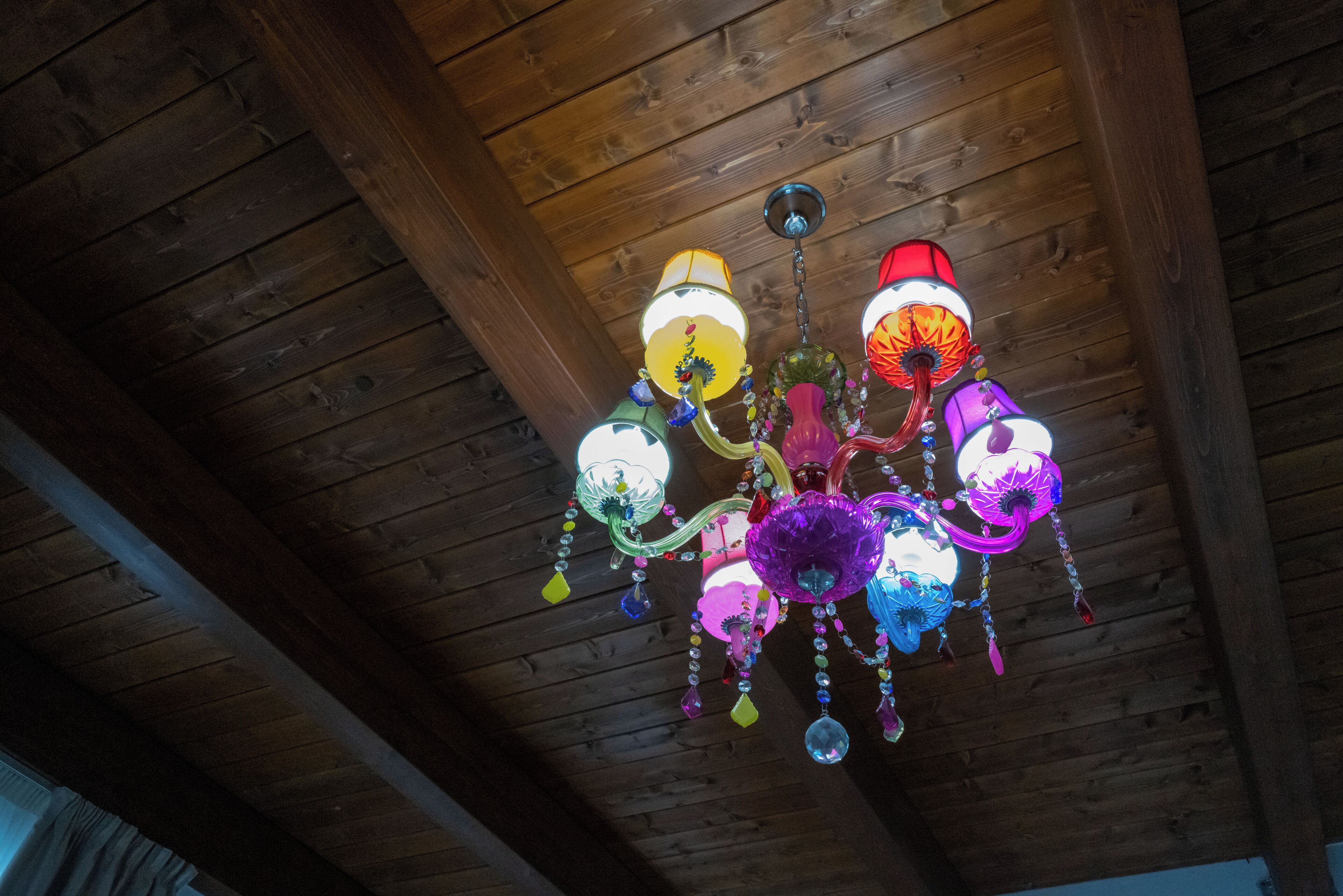 Een houten plafond met een kleurrijke kroonluchter.