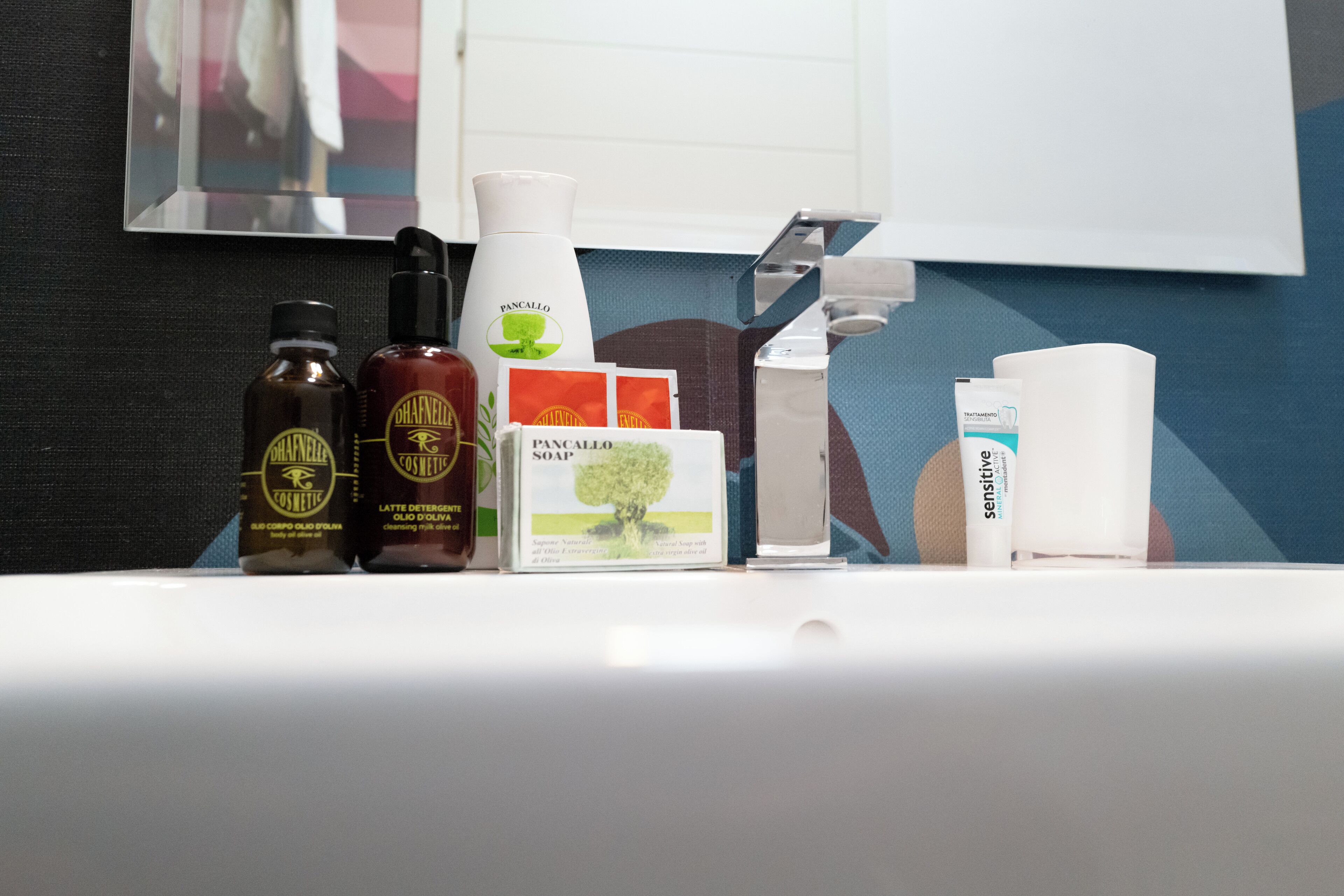 A bathroom counter with various toiletries including bottles of lotion, a bottle of soap, and a box of shampoo.