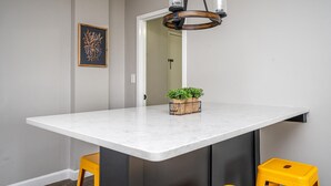 Een moderne keuken met een wit marmeren aanrechtblad, een hanglamp en een kleine plant in een pot.