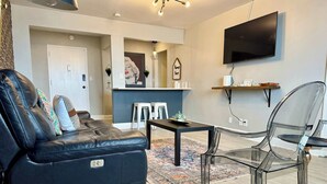Un salon moderne avec un canapé en cuir, une table en verre et une chaise transparente.
