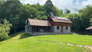 A rustic stone house with a sloped roof and a small attached wooden structure. - Charming 2bed Cottage in Carasova, Banat Mountains (Carasova)