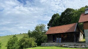 A stone house with a red-tiled roof, surrounded by a grassy field and trees. - Charming 2bed Cottage in Carasova, Banat Mountains (Carasova)