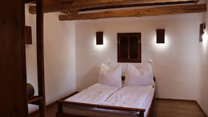 A bedroom with a wooden bed frame, white bedding, and two wall-mounted light fixtures. - Charming 2bed Cottage in Carasova, Banat Mountains (Carasova)