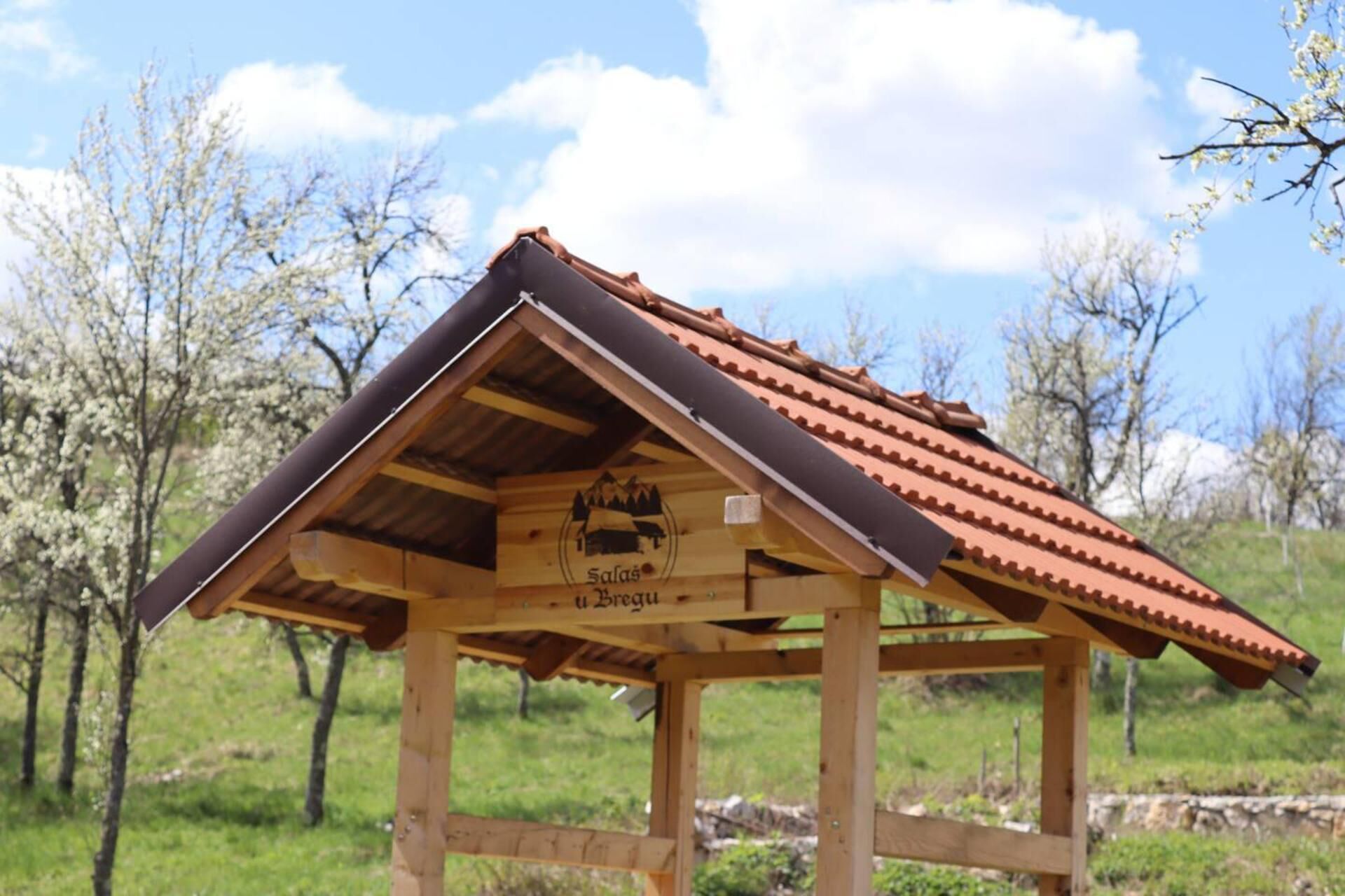 A wooden birdhouse with a sloped roof and a sign that reads "Saal's Bregu."