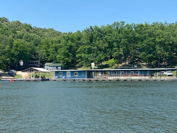 A lakeside building with a covered dock area, surrounded by dense forest.