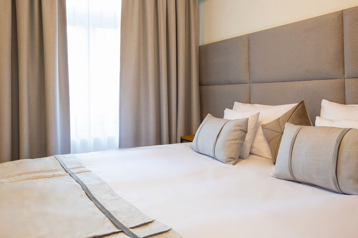 Hotellihuone, jossa on suuri sänky, pääty ja verhot.