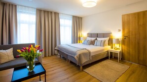 Een hotelkamer met een bed, nachtkastjes, een bank, een bloemetjesvaas en een houten garderobe.