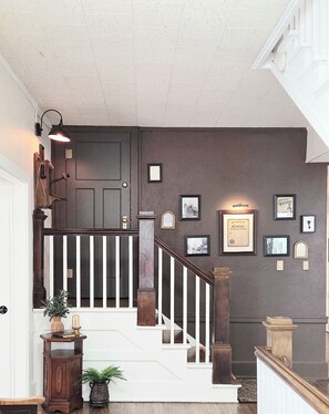 A staircase with a white railing, a dark door, and a wall adorned with framed pictures and certificates. - Magnolia Manor and Chapel (Humboldt)