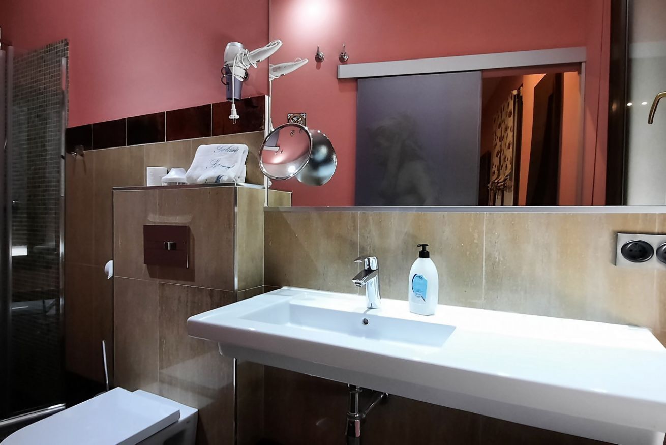 Un baño moderno con lavamanos blanco, un espejo y un espejo de mano.
