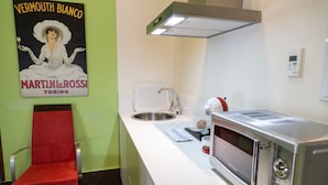 A kitchen with a microwave, sink, and a chair. - Estudio Deluxe 2 Personas (Andújar)