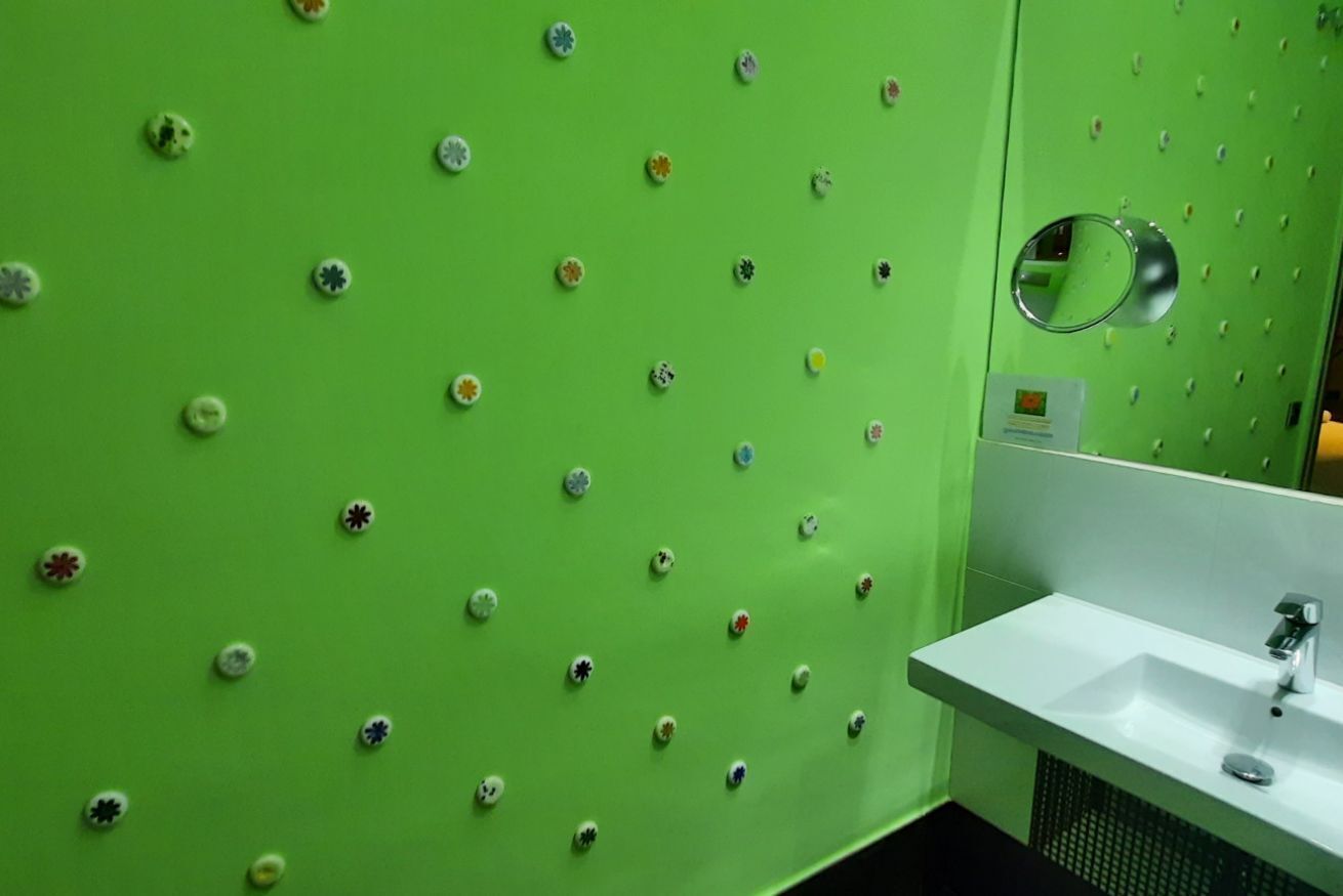 A bathroom with a green wall, a white sink, and a mirror.