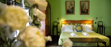 A room with a bed, two paintings on the wall, and a wooden headboard.