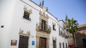 A historic building with a central wooden door, ornate balconies, and a sign indicating it is a palace. - Estudio Deluxe 2 Personas (Andújar)