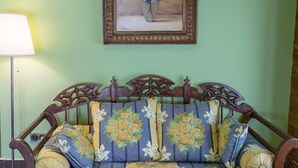 A room with a wooden bed with floral-patterned bedding, a framed painting on the wall, and a floor lamp. - Estudio Deluxe 2 Personas (Andújar)