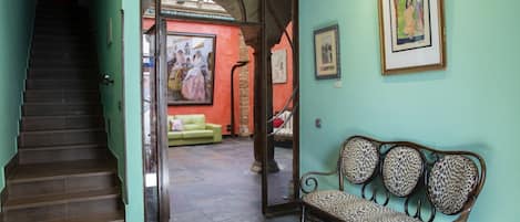 A staircase leading to a room with a green wall, a bench, and a painting.