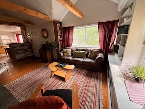 A cozy living room with a brown leather sofa, a wooden coffee table, and a striped rug.