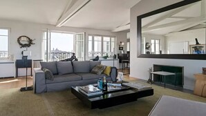 Ein geräumiges Wohnzimmer mit grauem Sofa, einem schwarzen Couchtisch und einem Kamin.