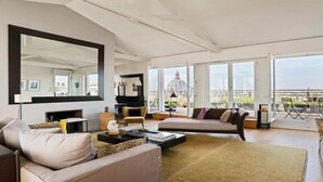 Ein geräumiges Wohnzimmer mit großem Spiegel, einem Klavier und einer Couch.