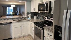 Una cocina moderna con armarios blancos, encimera de granito, electrodomésticos de acero inoxidable y dispensador de agua.