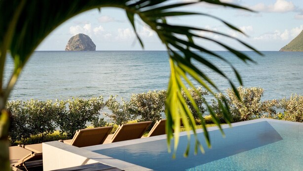 A poolside area with lounge chairs and a view of the sea and a distant island. - Villa Orlov - Luxury villa on the water (Le Diamant)