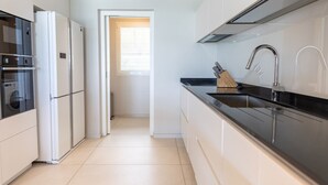 A modern kitchen with white cabinetry, a black countertop, and stainless steel appliances. - Villa Orlov - Luxury villa on the water (Le Diamant)