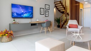 Un soggiorno moderno con una televisione a schermo piatto, una scala in legno e una zona pranzo.