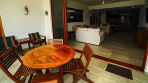 Un comedor con una mesa redonda de madera y sillas, un sofá y un televisor al fondo.