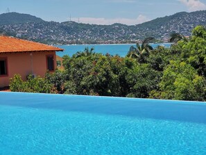Una piscina con vista su una località costiera e colline sullo sfondo.