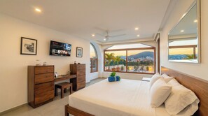 Une chambre à coucher avec un lit, un bureau, une télévision et une fenêtre donnant sur la ville.