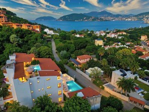 A residential area with a swimming pool, multiple buildings, and a view of the sea.