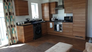 Eine moderne Küche mit Holzausstattung, Backofen, Mikrowelle und Waschmaschine.