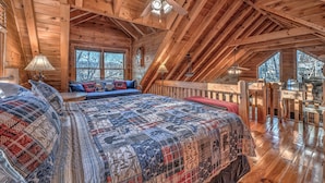 A log cabin bedroom with a large bed, a ceiling fan, and a view of the outdoors through the windows. - Treetop 3br Cabin- Hot tub, Fireplace, Firepit, Grill, Fast Wi-Fi & Dog-Friendly (Blue Ridge)