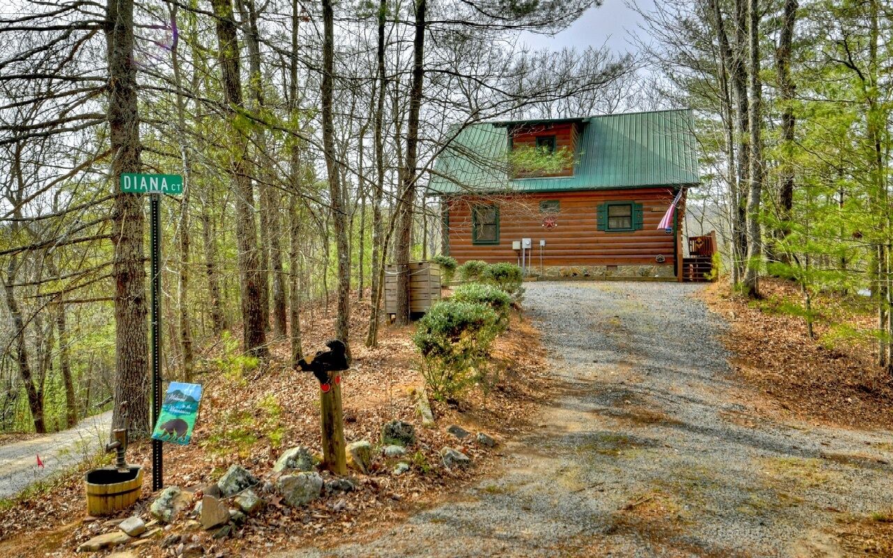 Une cabane située à l’intersection de Diana Court, avec une allée de gravier menant à celle-ci, et entourée d’arbres.