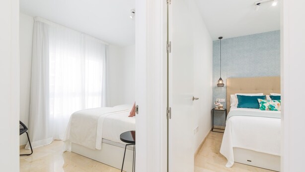 Een hotelkamer met twee bedden, een kleine tafel, een stoel en een nachtkastje met een lamp.