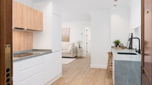 A modern kitchen with white cabinetry, a grey countertop, and a wooden floor.