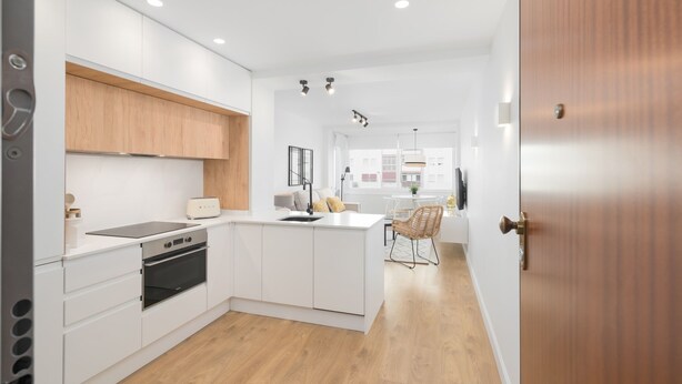 Una cocina moderna con armarios blancos, horno empotrado y una isla central.