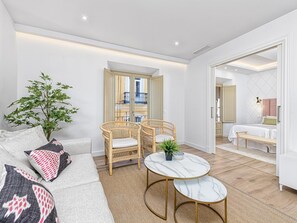 Un salon moderne avec un canapé, deux fauteuils en osier, une petite table ronde et une plante en pot.