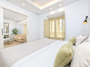 Quarto moderno com uma cama grande, uma escrivaninha e uma cadeira, e um guarda-roupa com portas de vidro.
