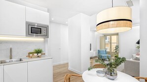 A modern kitchen with white cabinetry, a built-in microwave, and a pendant light.