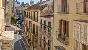 A narrow street flanked by multi-story buildings with balconies, a cobblestone path, and a distant tower. - iloftmalaga Madre de Dios V - 2B (Málaga)