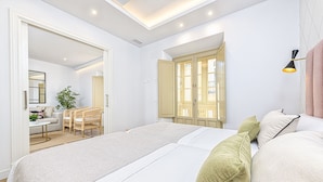 A modern hotel room with a large bed, a desk, and a chair. There is a window with open shutters and a plant on the desk. - iloftmalaga Madre de Dios V - 2B (Málaga)
