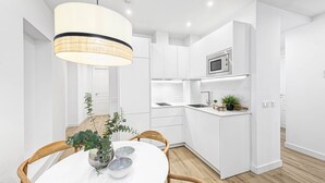 Una cocina moderna con armarios blancos, una isla central y un colgante de techo.