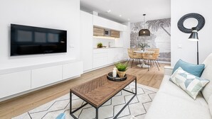Una sala de estar moderna con un televisor de pantalla plana, una mesa de centro de madera y un sofá con cojines estampados.