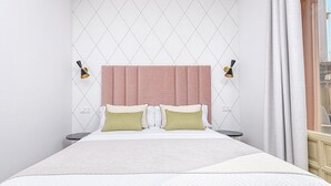 A neatly arranged hotel room with a large bed, two bedside tables, and a headboard with a textured design.