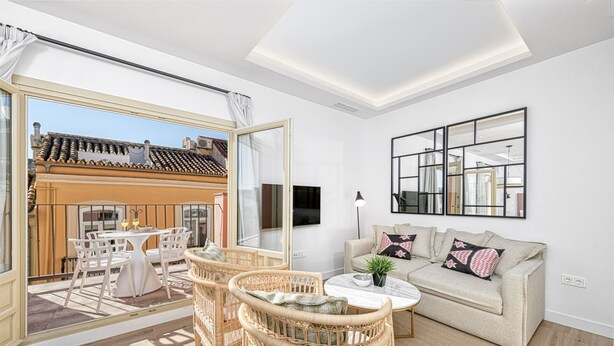 A spacious living room with a sofa, wicker chairs, a coffee table, and a TV.