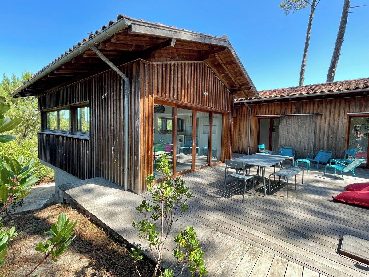 Une cabane en bois dotée d’une terrasse, d’un espace salon extérieur et d’un petit jardin.