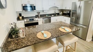 A modern kitchen with white cabinets, stainless steel appliances, and a granite countertop. - Boat lovers dream - waterfront unit with dock & walk to the beach (Orange Beach)
