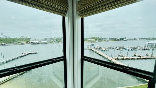 A view from a room with large windows overlooking a marina with boats and docks. - Boat lovers dream - waterfront unit with dock & walk to the beach (Orange Beach)