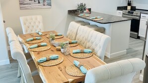 A modern kitchen with white cabinetry, a built-in microwave, and a dining area with a wooden table set for six. - Boat lovers dream - waterfront unit with dock & walk to the beach (Orange Beach)